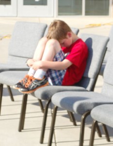 A Dacusville Elementary student sits with his head down during a community service held in honor of Carly and Sawyer Simpson at the school last Thursday. (Emily Wright/Courier)